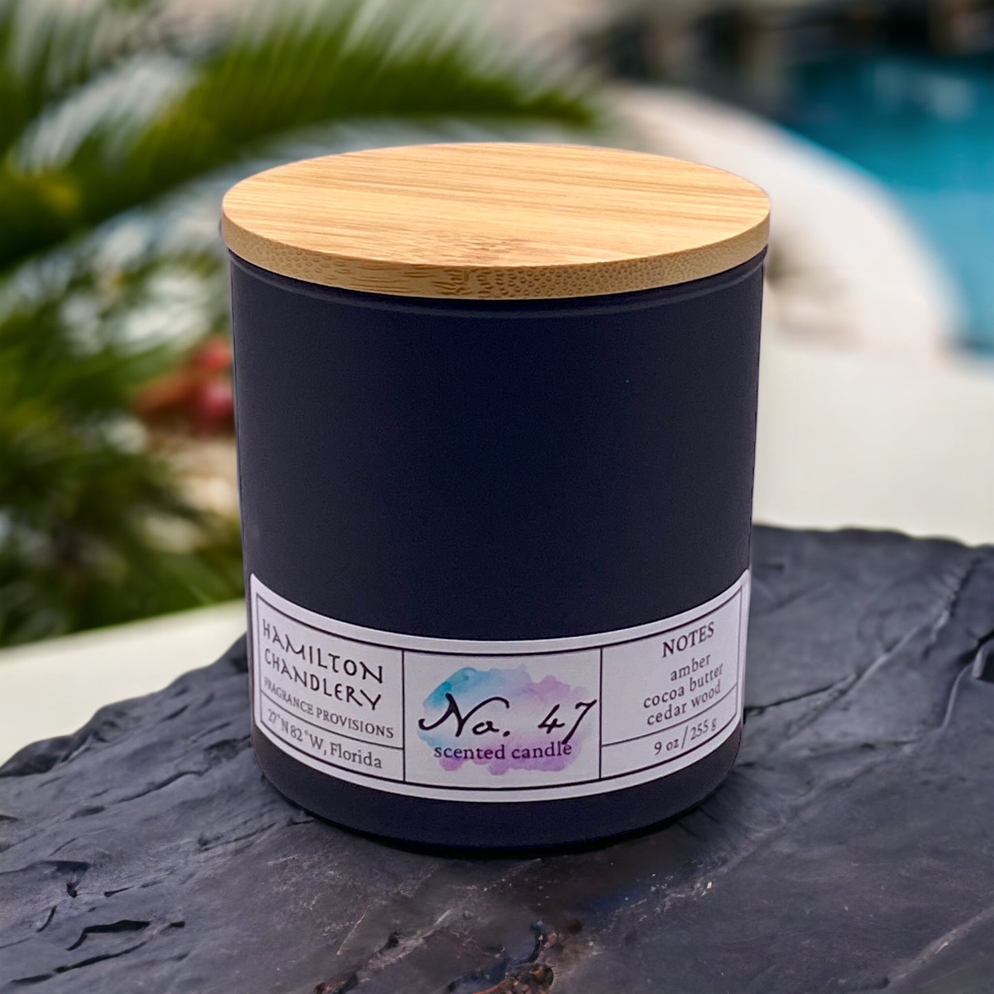 Fragrance No. 47 Blown Glass Candle on Slate with Palm Trees and Resort Pool in Background | Hamilton Chandlery