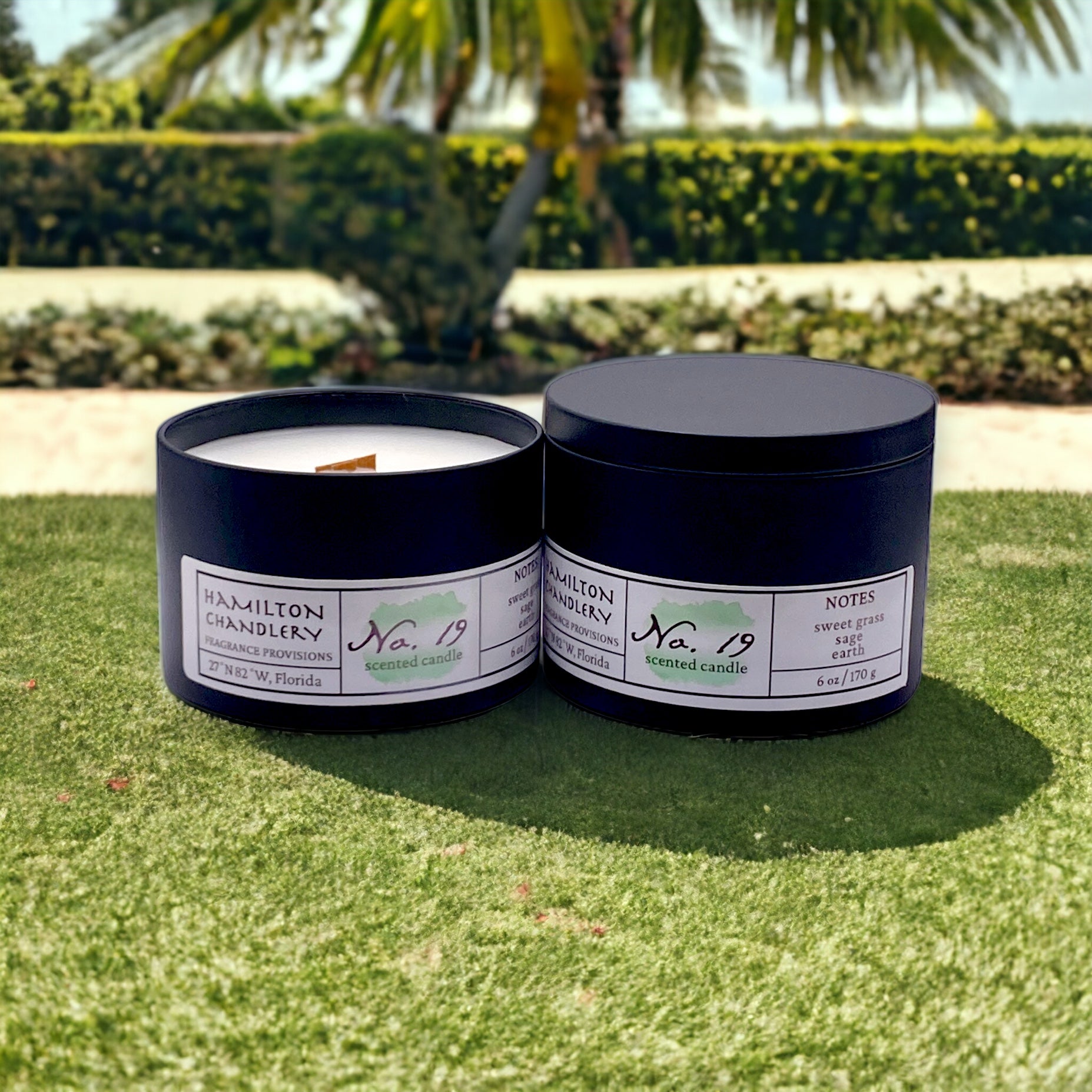 Fragrance No. 19 Travel Tin Candles on Fresh Cut Grass with Palm Trees in Background | Hamilton Chandlery